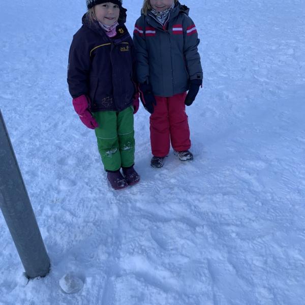 Zwei Mädchen haben den Buchstabe F in den Schnee geschrieben