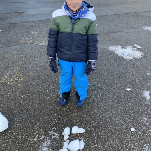 Ein Junge hat den Buchstaben F aus Eisklötzen gelegt