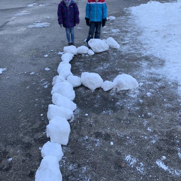 Zwei Mädchen haben den Buchstaben F aus Eisklötzen gelegt